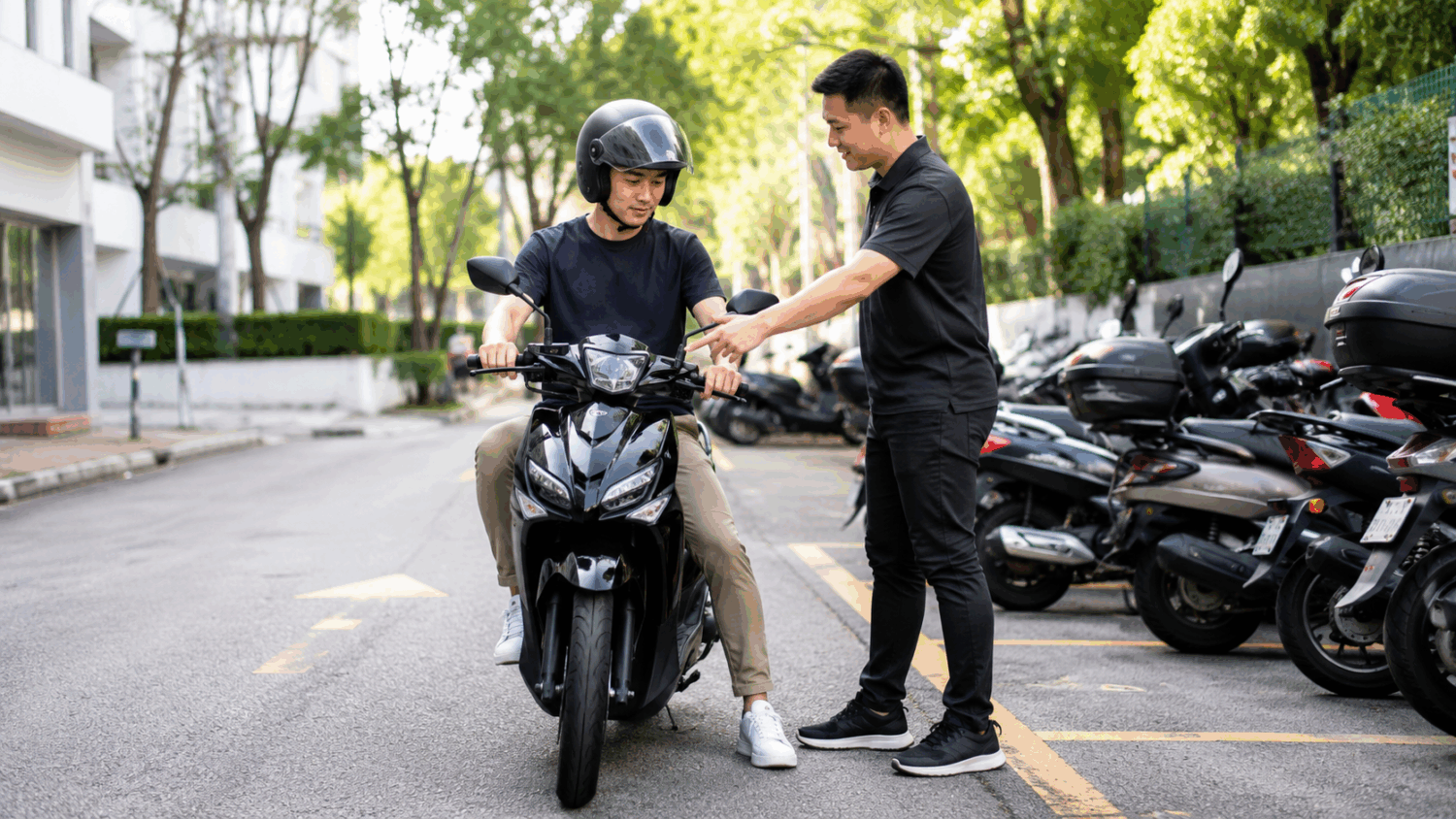 Customer test riding a motorcycle before rental while a rental staff member provides assistance at a motorcycle rental location in Singapore.